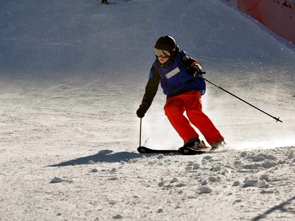 Skifahrerin in roter Hose auf der sonnigen Piste.